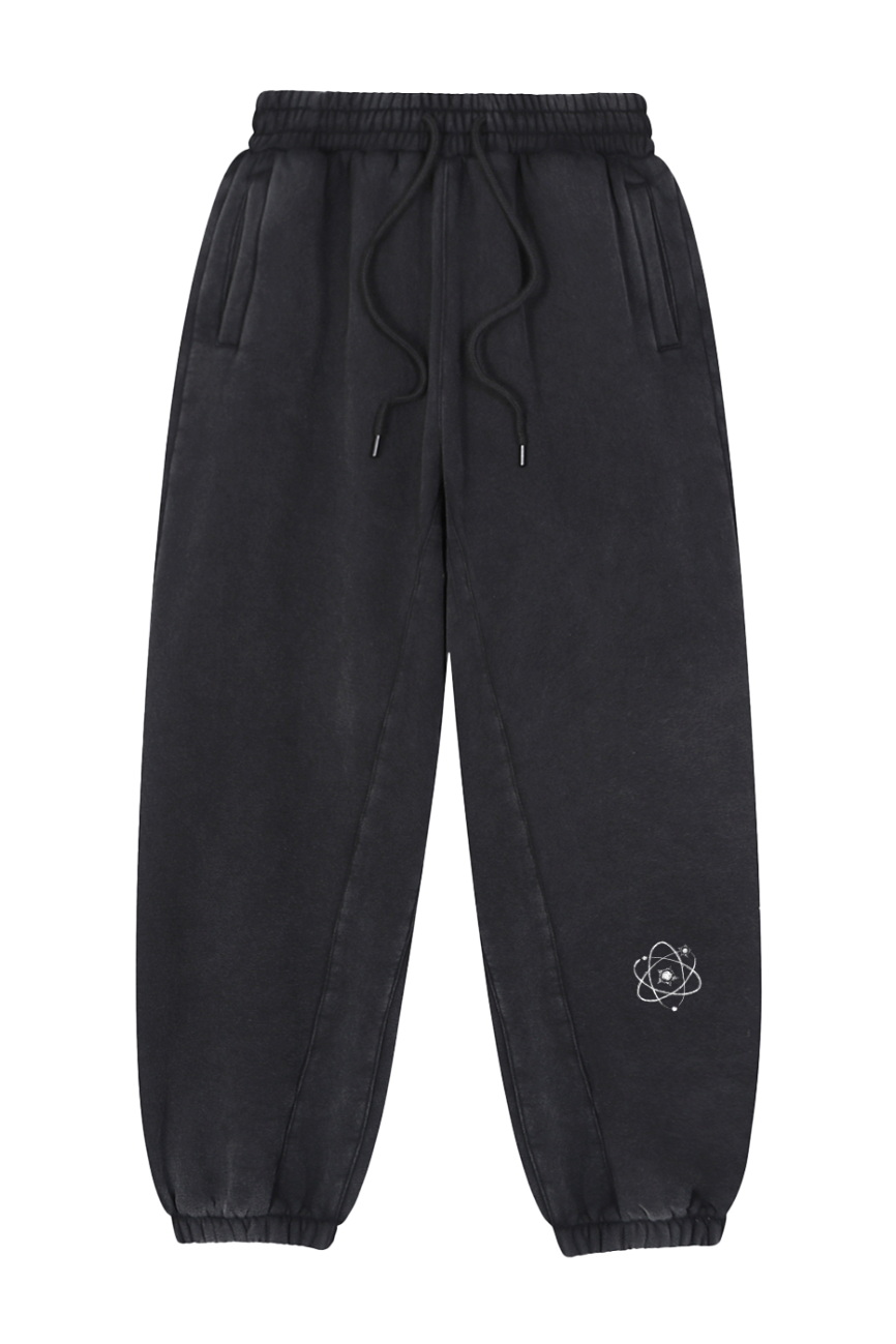 The Fusion Core -Fleeced Jogger Sweatpants feature an elastic waistband with a drawstring, side pockets, and elastic cuffs. A small white atom graphic on the left thigh adds a stylish touch. Shown on a plain white background.