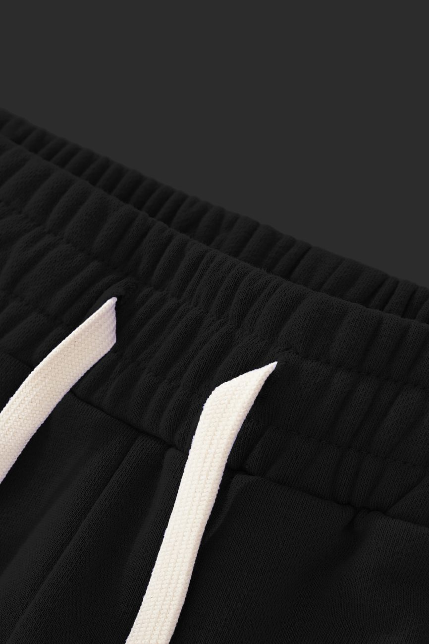 Close-up of the waistband of Sun Fade Raw Edge Cotton Shorts with an elastic band and white drawstrings, showcasing affordable luxury and attention to comfort and detail against a dark background.