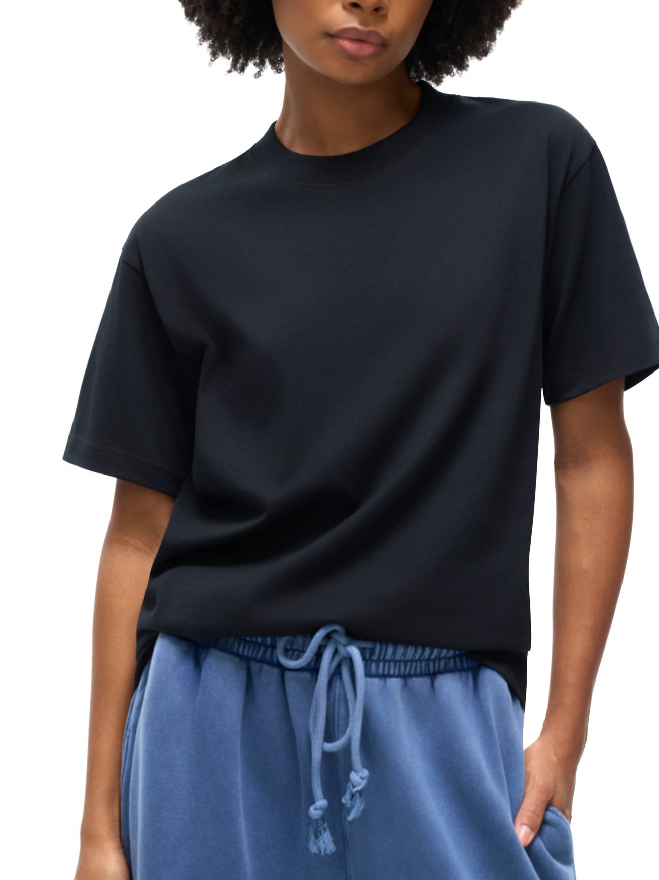 A person wearing our Fusion Oversized T-shirt in black and blue drawstring pants from the Affordable Luxury Clothing line stands against a white background, with the image cropped at the forehead and mid-thigh.