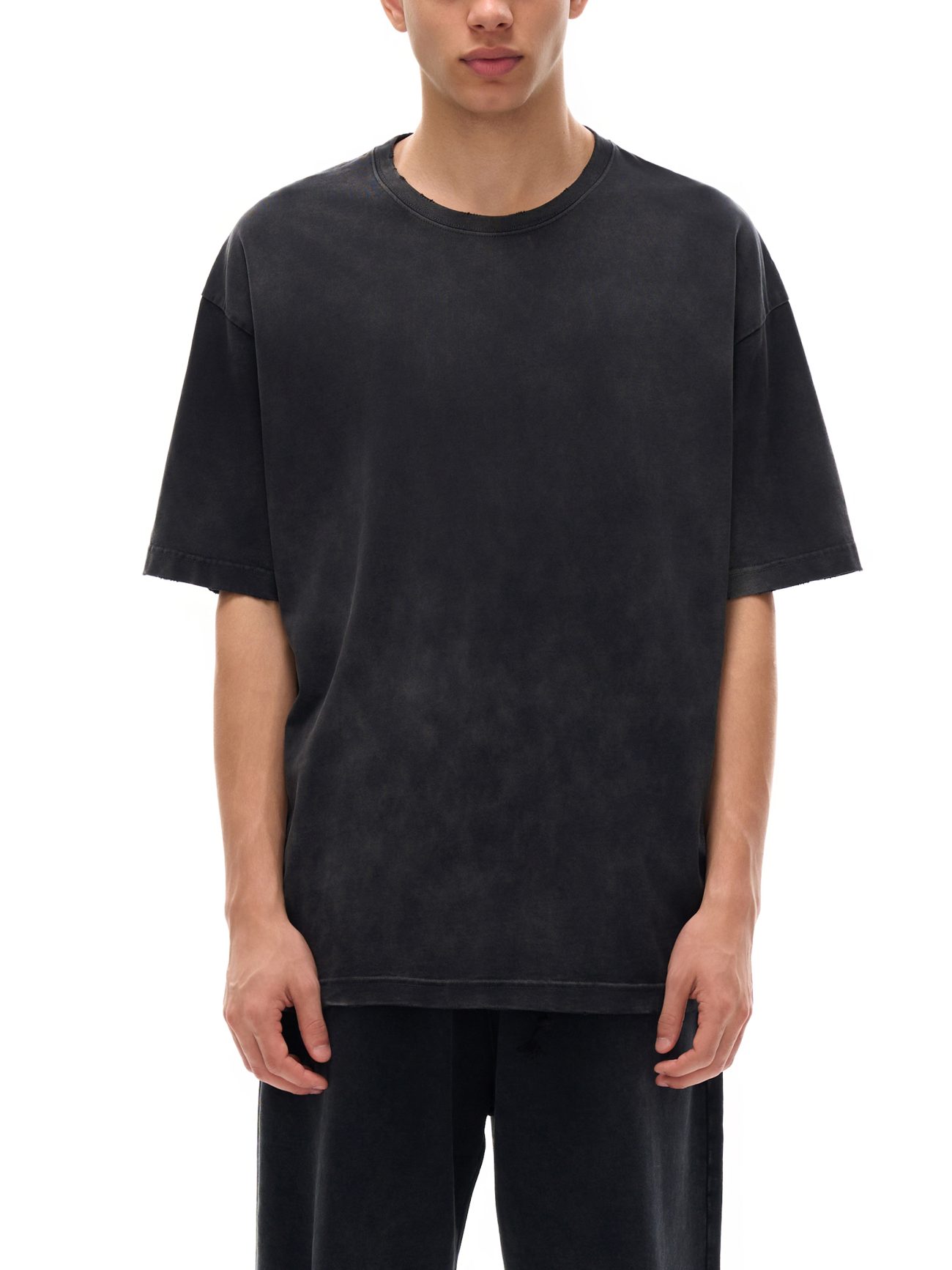 Wearing the Fusion Atom - Vintage Washed Hand-Frayed T-Shirt and black pants, someone models effortless affordable luxury in loose, faded black clothing against a white background, head partially out of frame.