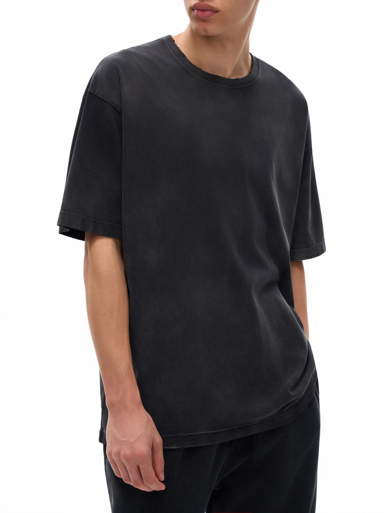 A person in the Fusion Vintage Washed Hand-Frayed T-Shirt and black pants—embodying affordable luxury—stands with one hand in their pocket against a white background. Their short hair and partially visible face add to the effortless style.