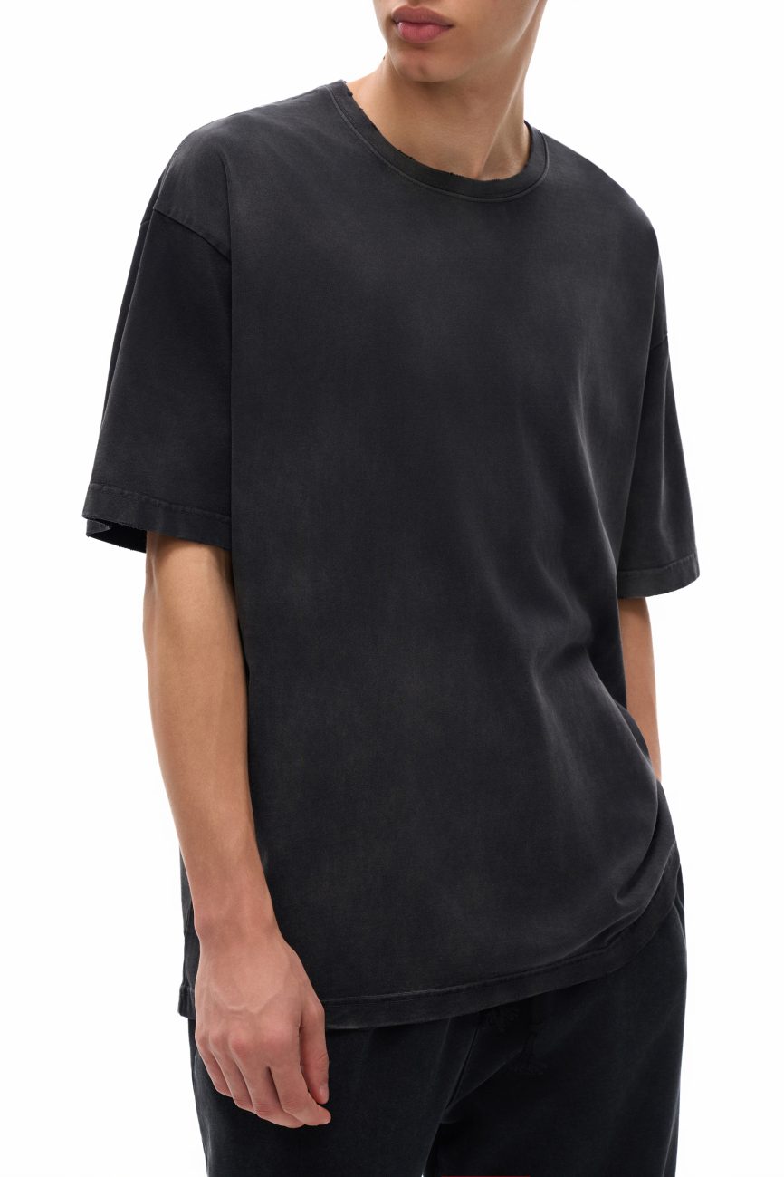 A person in the Fusion Vintage Washed Hand-Frayed T-Shirt and black pants—embodying affordable luxury—stands with one hand in their pocket against a white background. Their short hair and partially visible face add to the effortless style.
