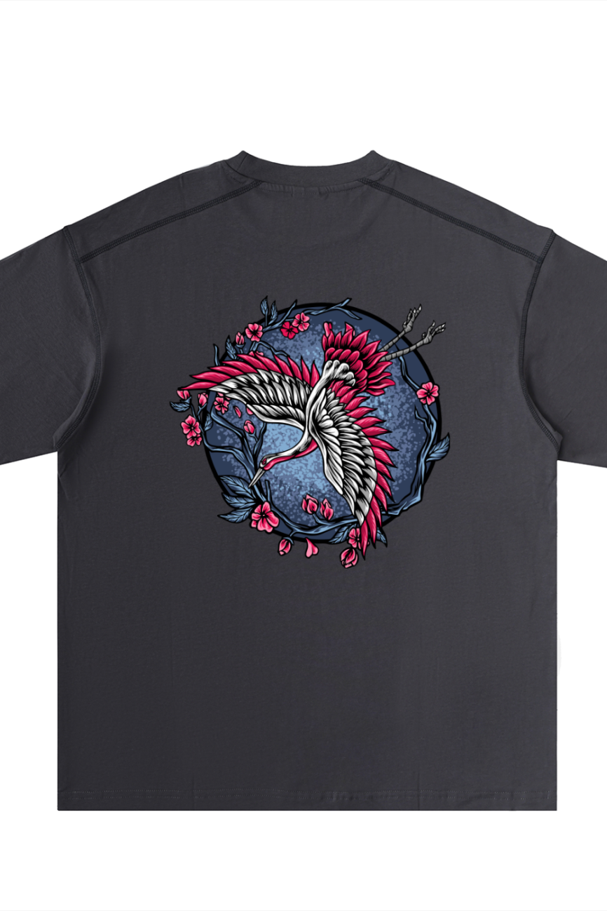 The Crane - Oversized Contrast-Stitched Cotton Tee features a black base with a vivid back graphic of a white and red crane among pink cherry blossoms and branches, all set against a blue circular background.