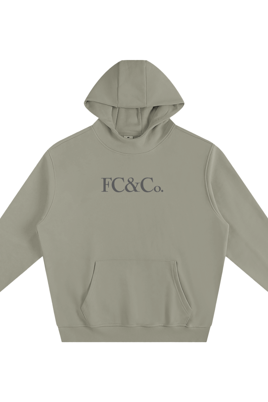 The Fleeced High Neck Hoodie features a light gray color, front pocket, large dark gray FC&Co. chest print, long sleeves, relaxed fit, and offers affordable luxury and elevated everyday comfort.