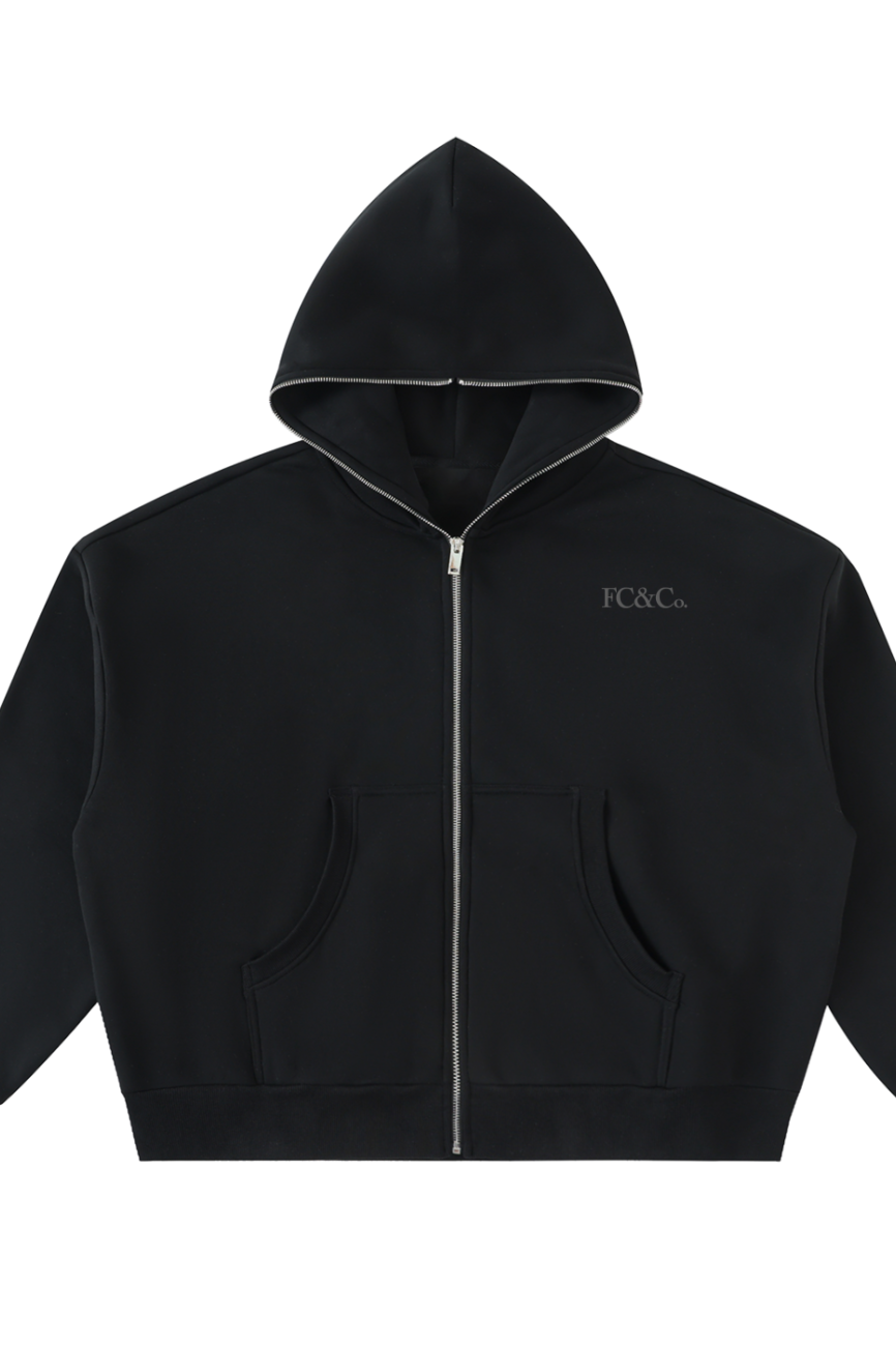 The FC&Co. Fleeced Full-Zip Boxy Hoodie features a black zip-up design with front pockets, hood, and small white FC&Co. print on the left chest—an affordable luxury essential for everyday wear.