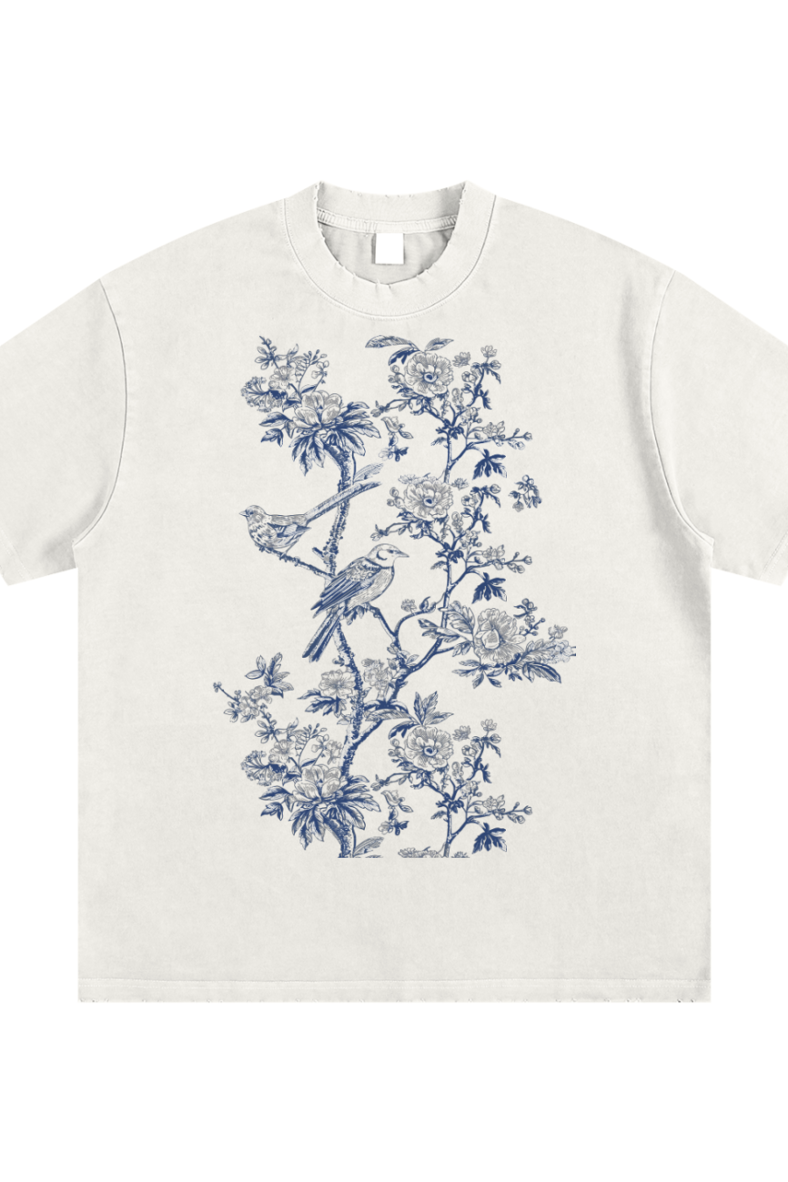 The Toile De Jouy - Heavyweight Vintage Washed Frayed T-Shirt features a detailed blue botanical and bird print on the front, combining vintage-inspired flowers and two perched birds for an affordable touch of luxury.