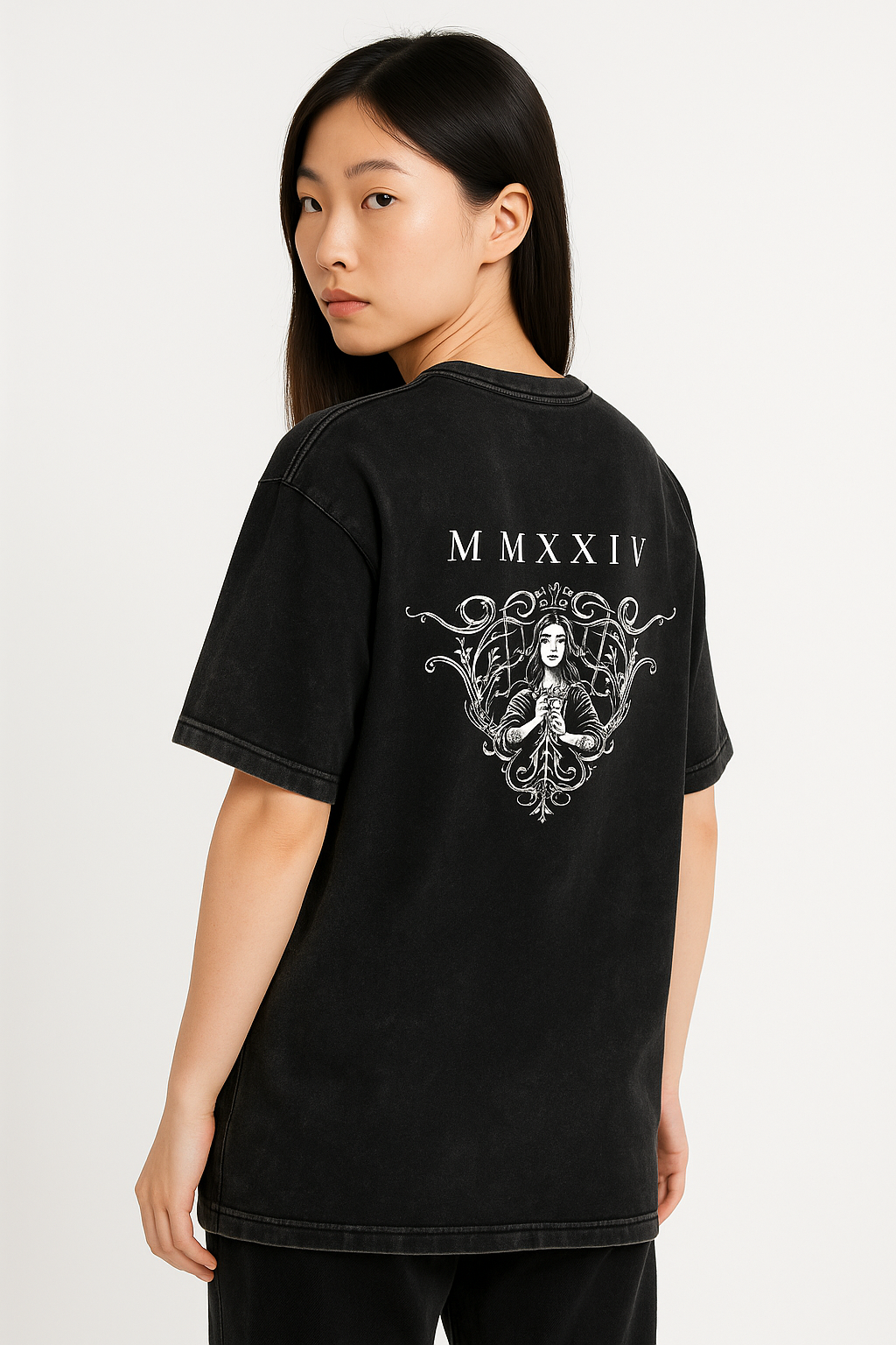 A woman with long, straight hair models the Acid Wash Oversize T-Shirt - 250 GSM, featuring a white MMXXIV graphic and ornate figure on the black back. She glances over her shoulder toward the camera.