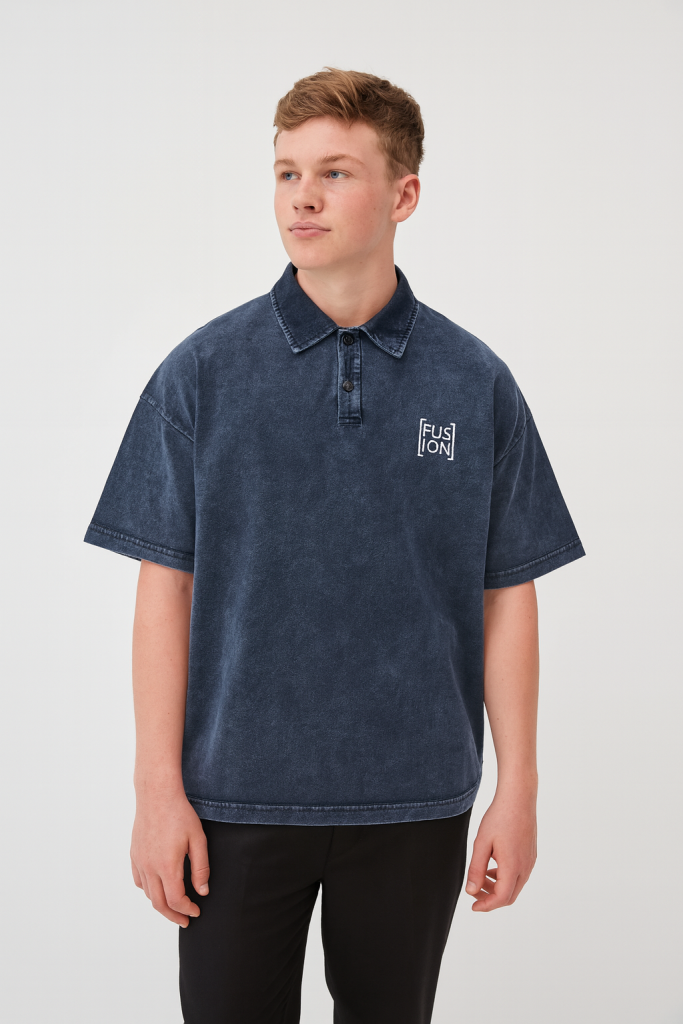 A young person stands against a plain background, wearing the Fusion Heavyweight Snow-Washed Polo T-Shirt in dark blue with a small white FUSION logo and black pants—perfect for those seeking affordable luxury.