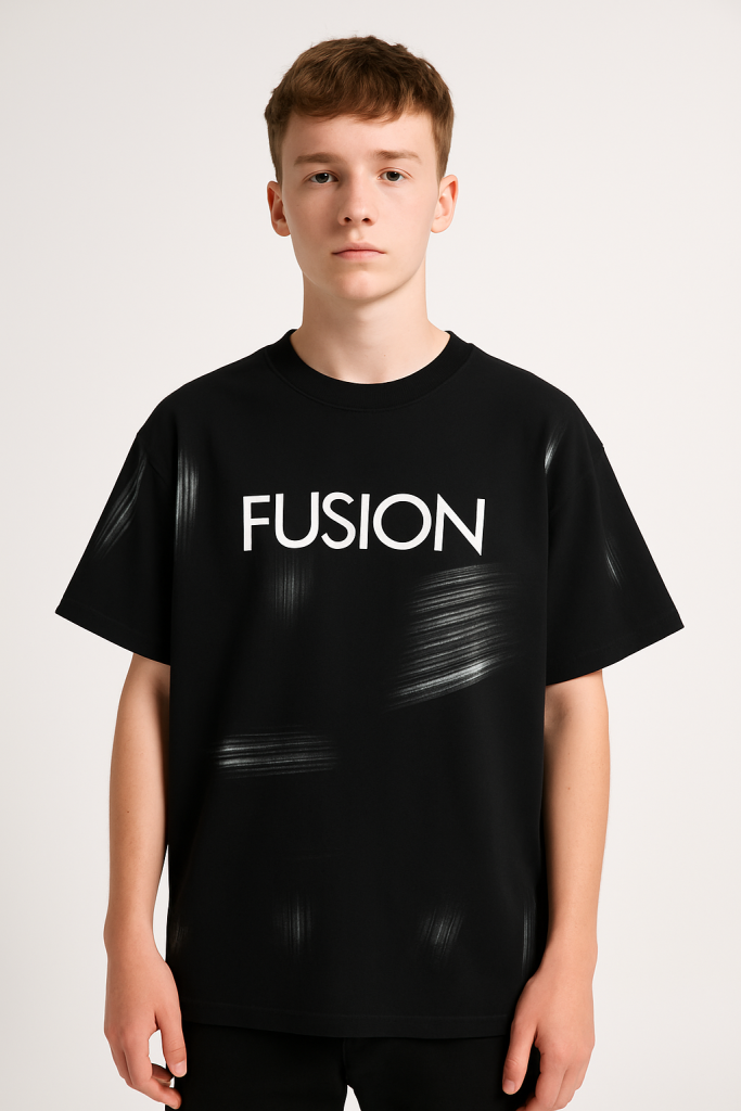 A young person with short brown hair stands against a plain light background, wearing a Hand Brushed T-shirt featuring FUSION in large white letters and subtle hand-brushed streak patterns across the chest.