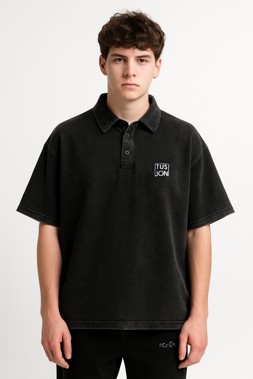 A young man with short brown hair wears a loose-fitting Heavyweight Snow-Washed Polo T-Shirt from TUSUON, representing affordable luxury clothing, standing against a plain white background.