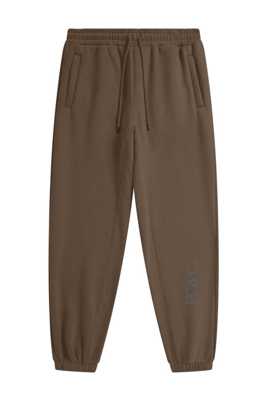 Streetwear Unisex Fleece Joggers in brown with an elastic waistband, drawstring, cuffed ankles, side pockets, and subtle FG&C Co. text near the left ankle—an affordable luxury staple—displayed on a white background.