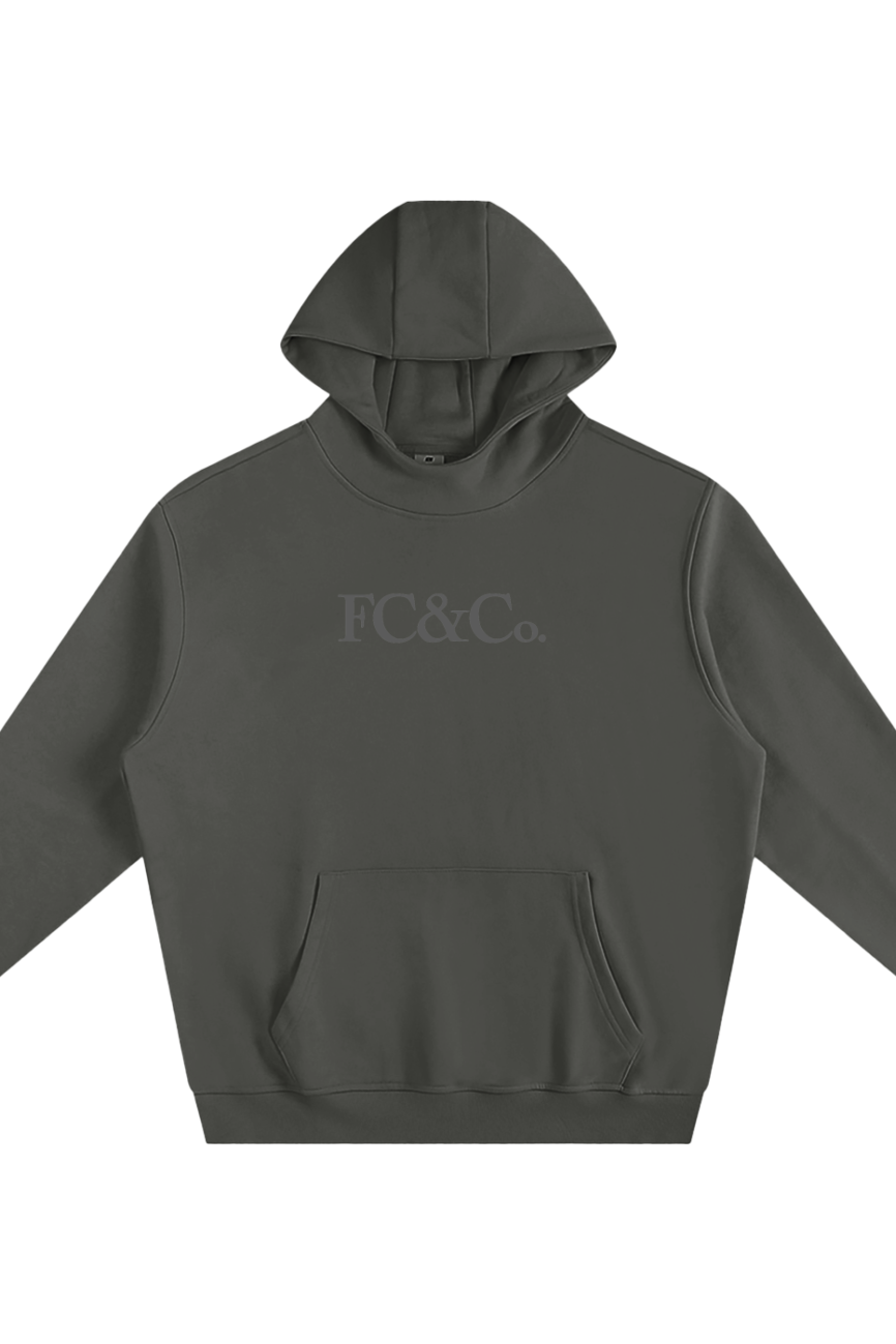 The Fleeced High Neck Hoodie in dark gray features a front kangaroo pocket and subtle FC&Co. chest print—an affordable luxury piece, shown laid flat on a white background.