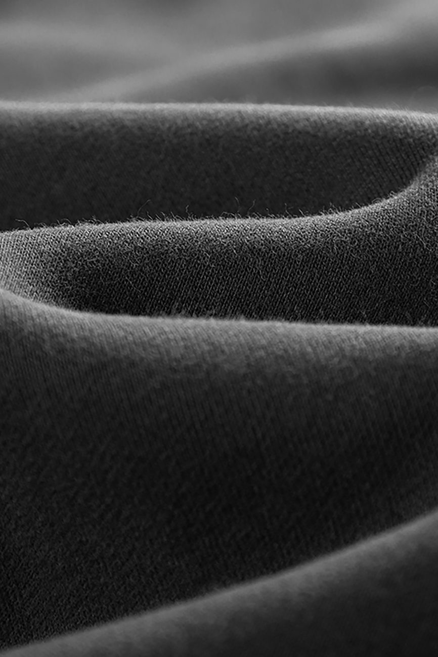 Close-up of the soft, black fabric on Streetwear Unisex Fleece Joggers shows gentle folds and a slightly textured surface, highlighting the smooth material and subtle shadows—reflecting affordable luxury quality.