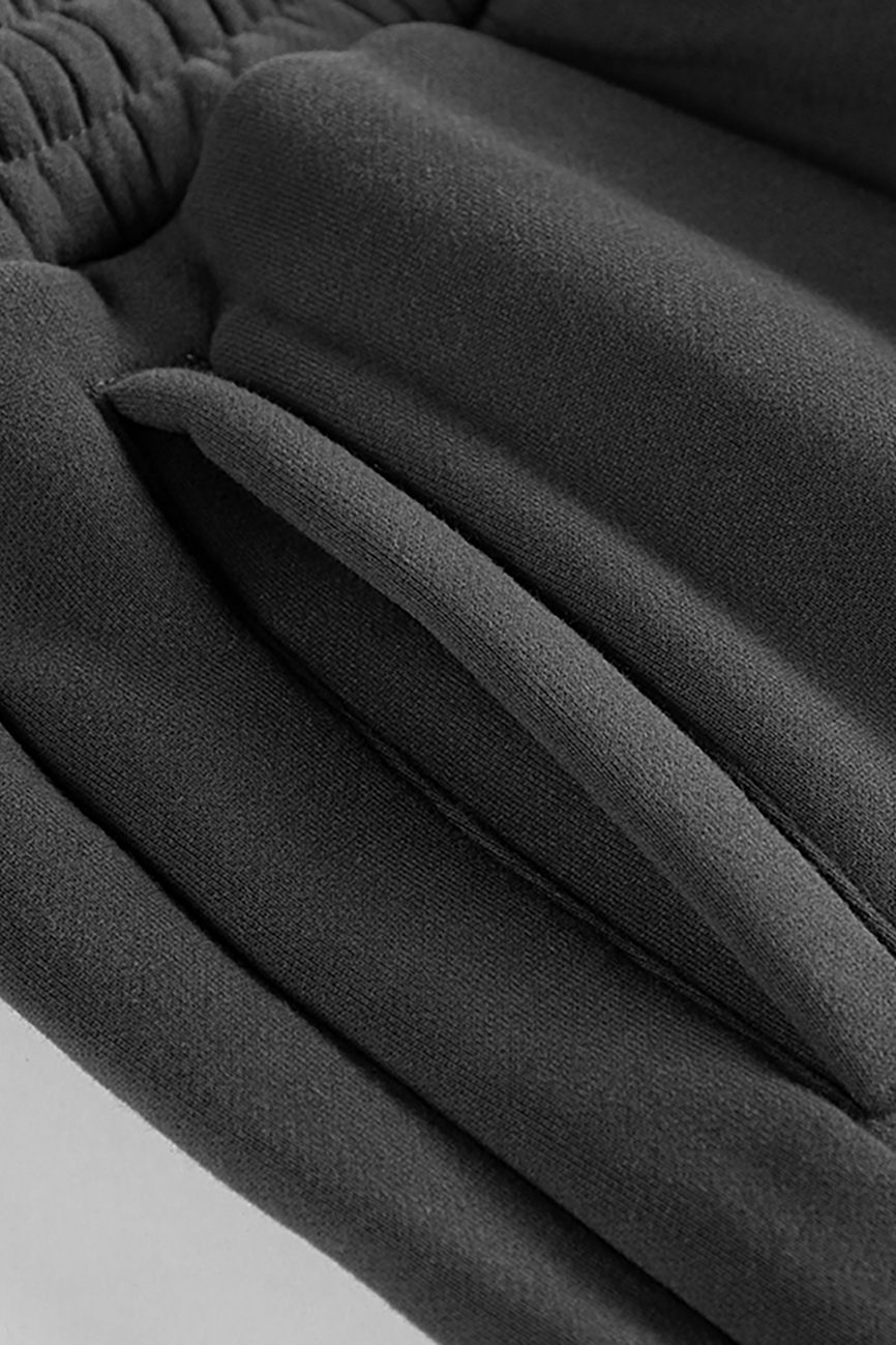 Close-up of black Streetwear Unisex Fleece Joggers, featuring an elastic waistband and slanted side pocket, made from soft, slightly textured fabric—part of our Affordable Luxury Clothing line.