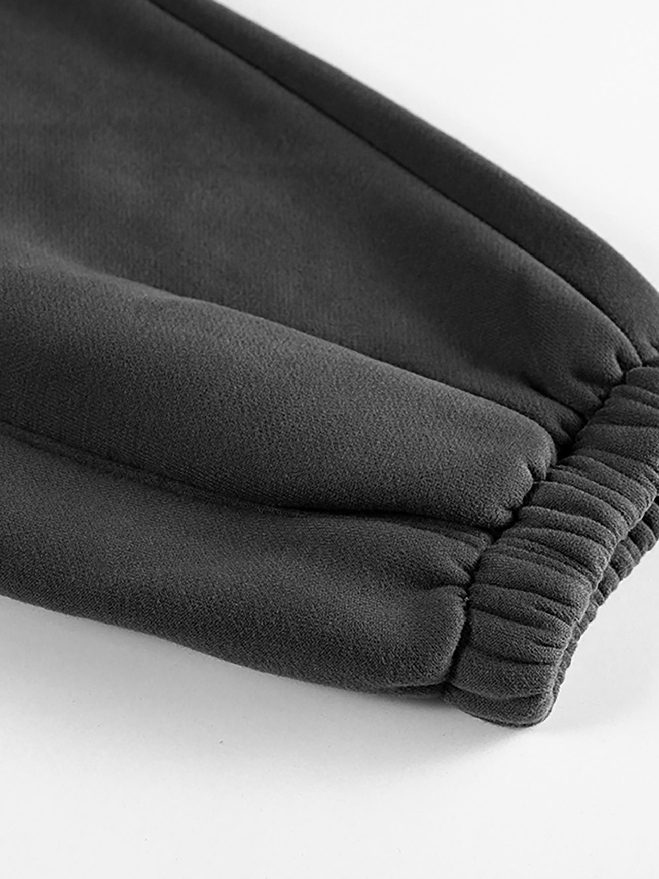 Close-up of the cuff on our Streetwear Unisex Fleece Joggers in dark gray, featuring gathered elastic at the ankle and showcasing the soft, smooth fleece texture.