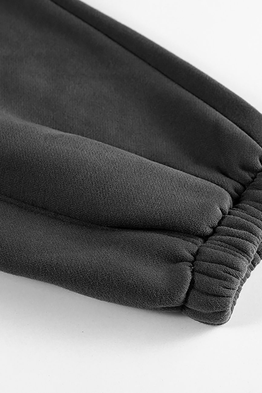 Close-up of the cuff on our Streetwear Unisex Fleece Joggers in dark gray, featuring gathered elastic at the ankle and showcasing the soft, smooth fleece texture.