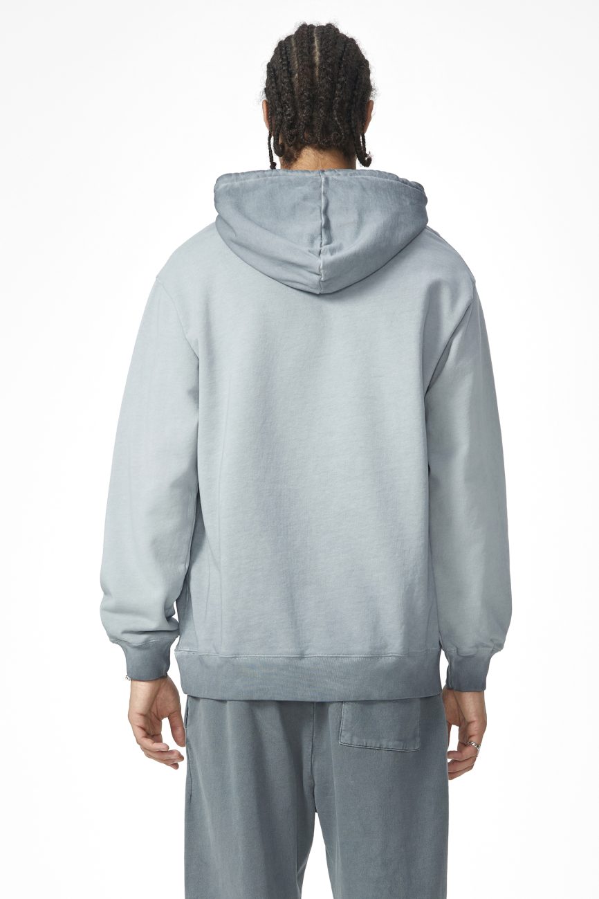 A person with braided hair is shown from behind wearing the FC&Co. Ombre Vintage Stone Washed Colorpointed Hoodie and matching sweatpants in light grayish-blue, set against a plain white background.