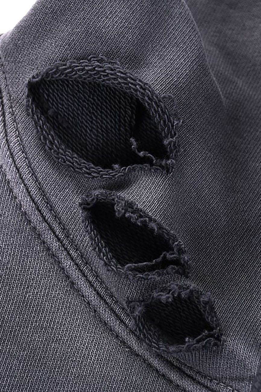 Close-up of the Heavyweight Pure Cotton Hand-Frayed Monkey Washed Hoodie by Company. Black fabric with three rough, oval holes and frayed edges along a seam; texture and stitching are clearly visible.