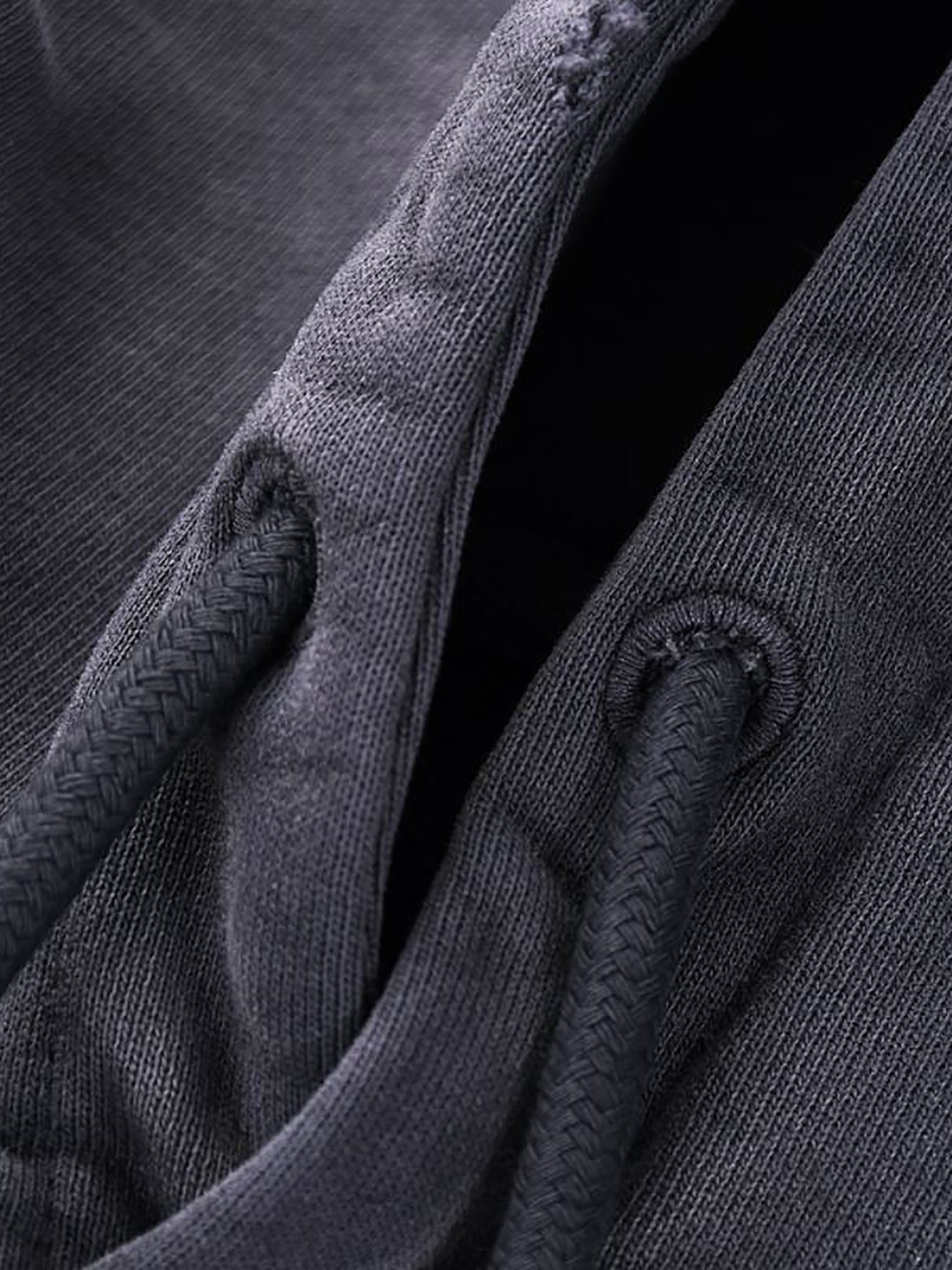 Close-up of dark gray fabric with two textured drawstrings through metal eyelets, highlighting the refined details of Company’s Heavyweight Pure Cotton Hand-Frayed Monkey Washed Hoodie—an affordable luxury piece.