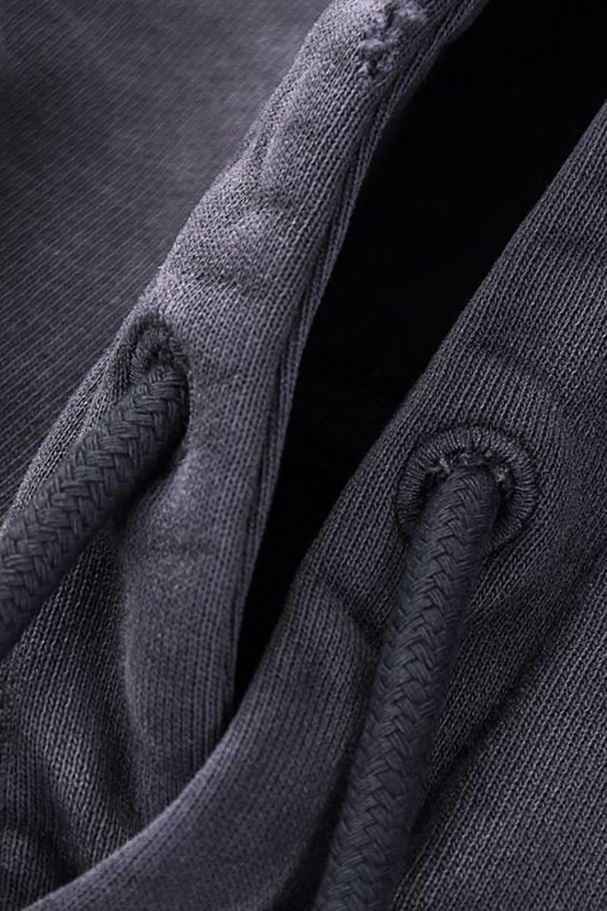 Close-up of dark gray fabric with two textured drawstrings through metal eyelets, highlighting the refined details of Company’s Heavyweight Pure Cotton Hand-Frayed Monkey Washed Hoodie—an affordable luxury piece.