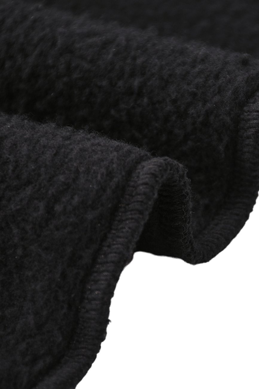 Close-up of the thick, black textured fabric used in Fleeced Jogger Sweatpants, featuring a soft, fuzzy surface and finished hem—perfect for affordable luxury clothing. Gentle, wavy folds highlight the materials comfort and quality.