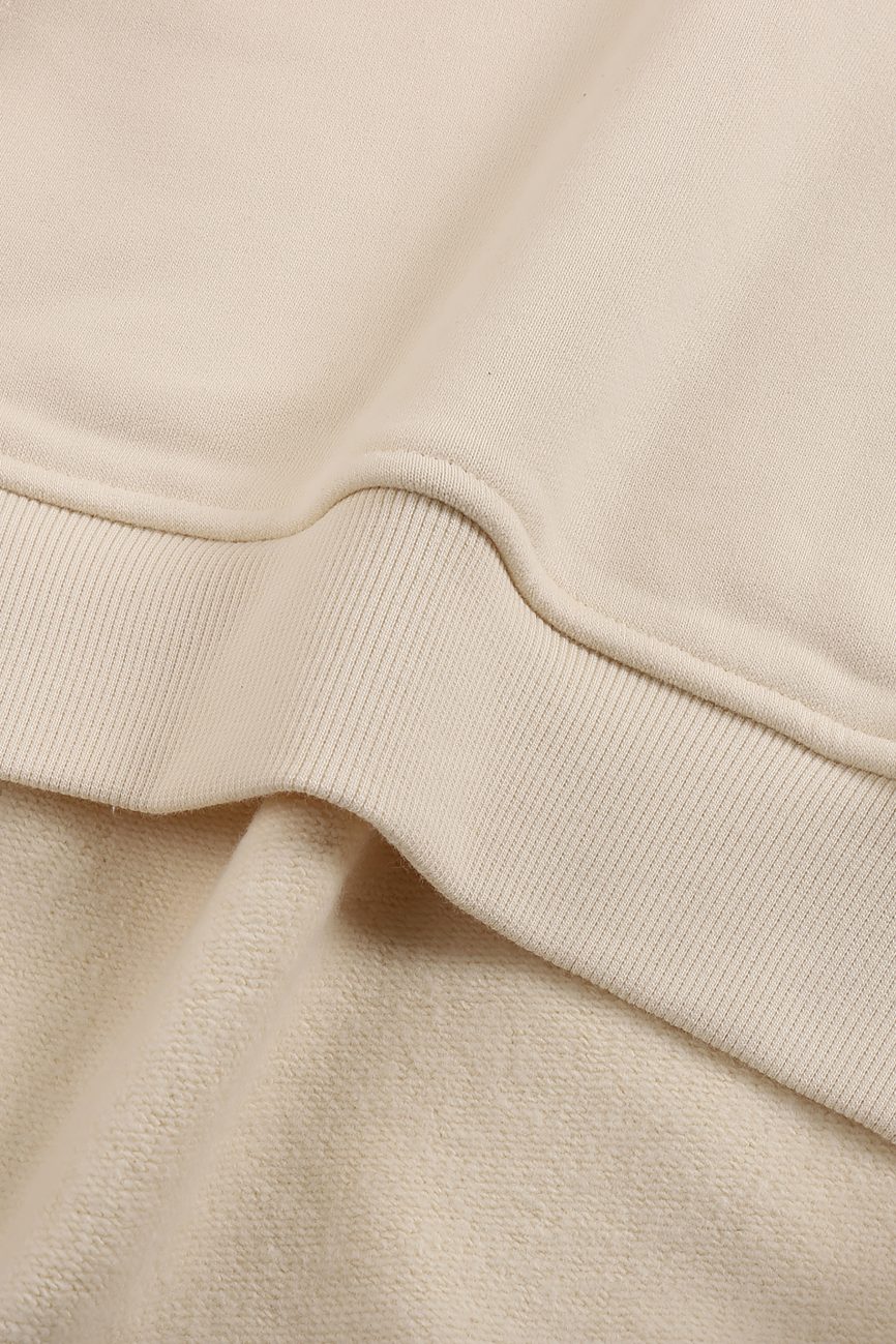 Close-up of the ribbed hem and soft fabric texture of the Fleeced High Neck Hoodie in beige, showcasing detailed stitching—an affordable luxury piece designed for everyday comfort.