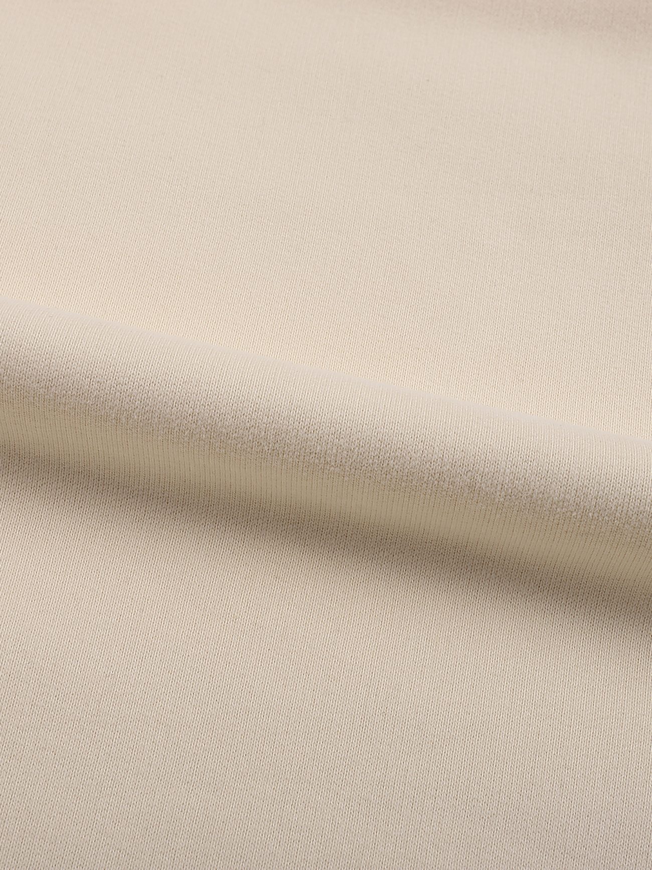 A close-up of light beige fabric with a subtle weave texture and a gentle diagonal fold—ideal for crafting the Fleeced High Neck Hoodie for affordable luxury.
