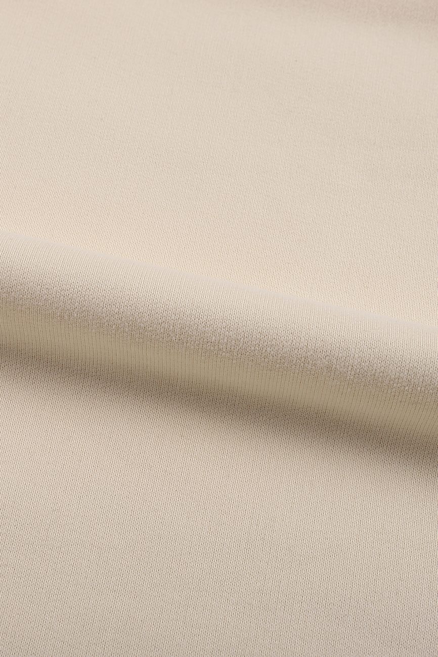 A close-up of light beige fabric with a subtle weave texture and a gentle diagonal fold—ideal for crafting the Fleeced High Neck Hoodie for affordable luxury.