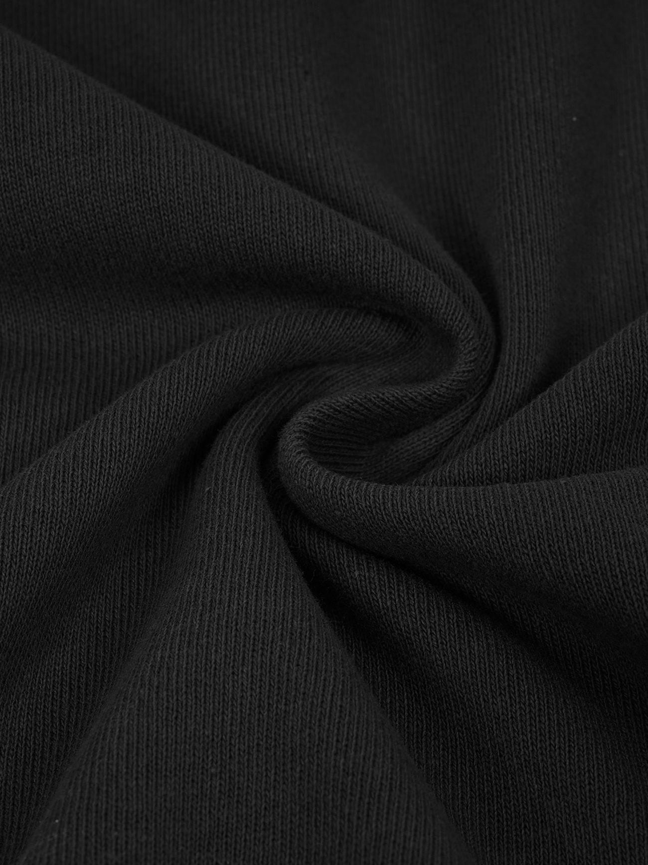 Close-up of black ribbed fabric on the Hand Brushed T-shirt, twisted into a swirl to highlight the texture and weave that define this piece of affordable luxury clothing.