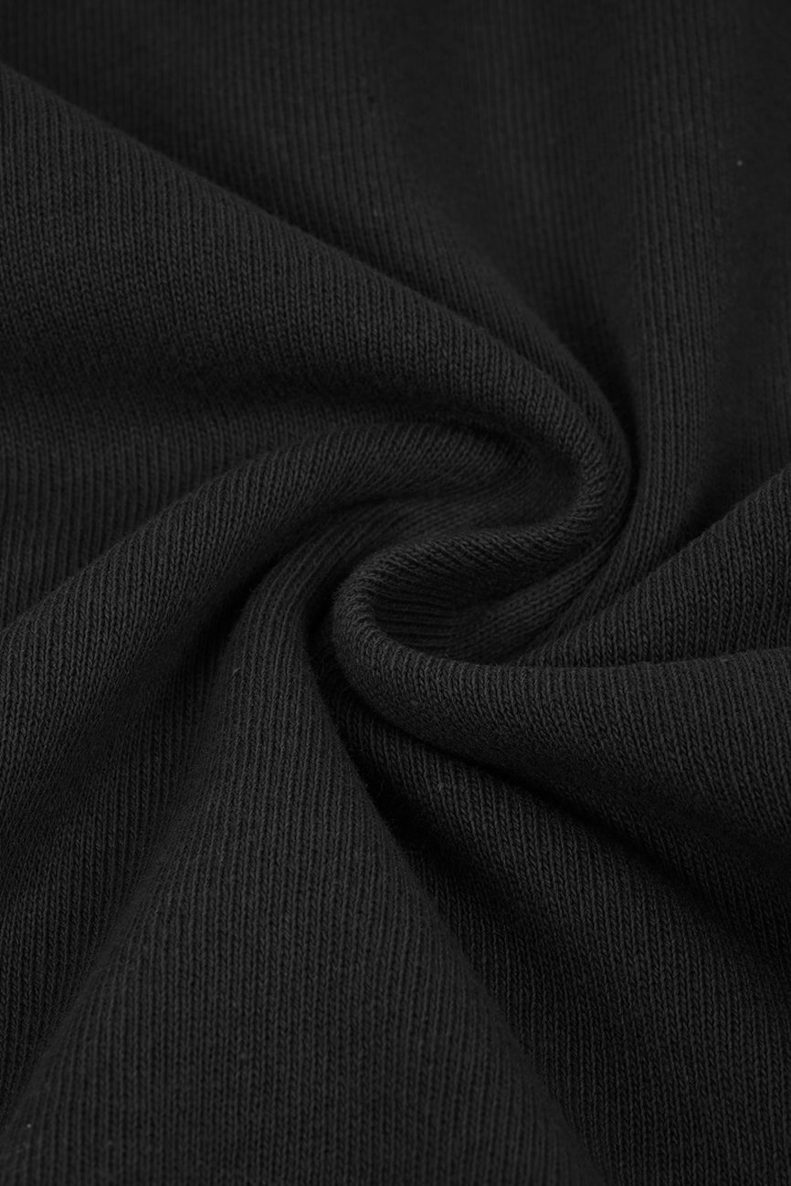Close-up of black ribbed fabric on the Hand Brushed T-shirt, twisted into a swirl to highlight the texture and weave that define this piece of affordable luxury clothing.