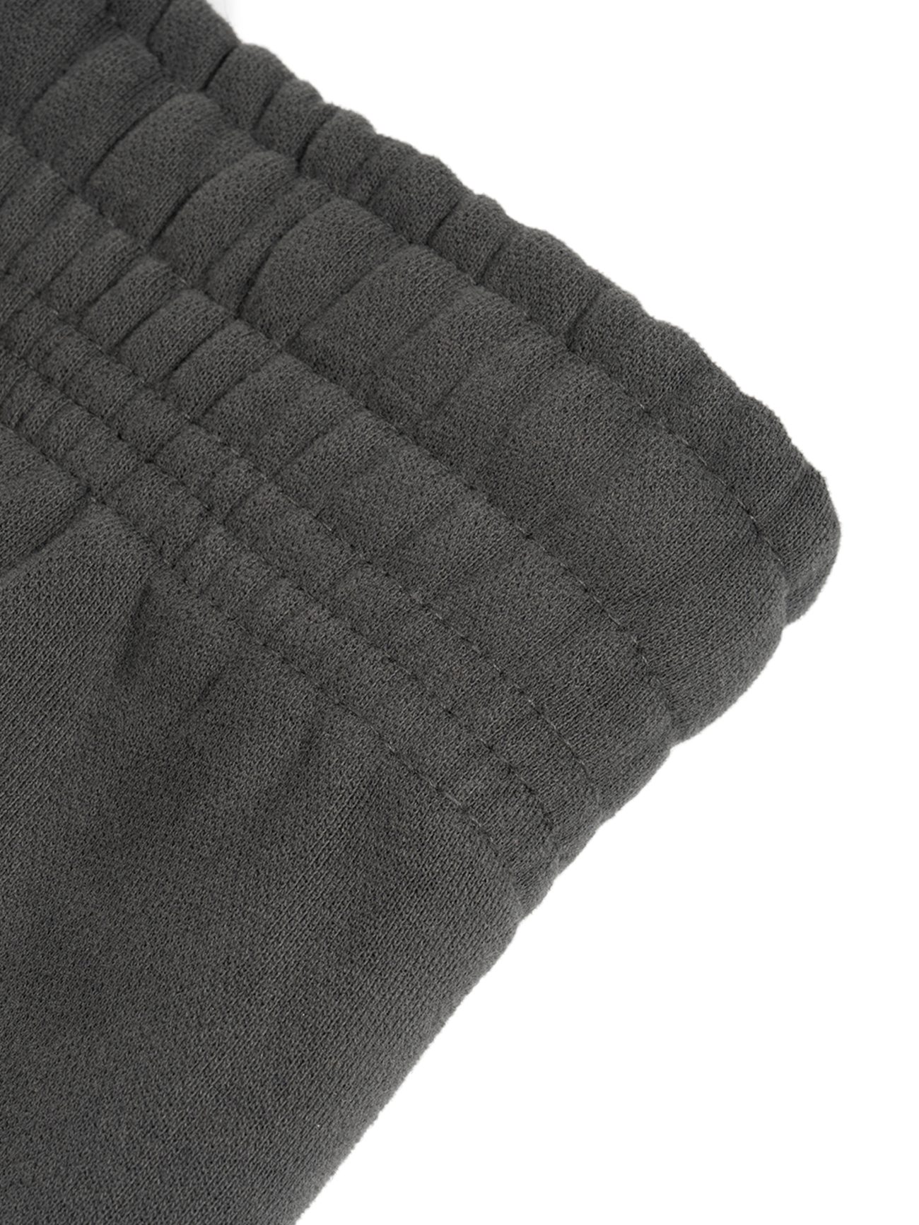 Close-up of the dark gray elastic waistband on Sunfade Curved Blade Fleece Sweatpants highlights detailed stitching and gathered fabric—showcasing affordable luxury craftsmanship.