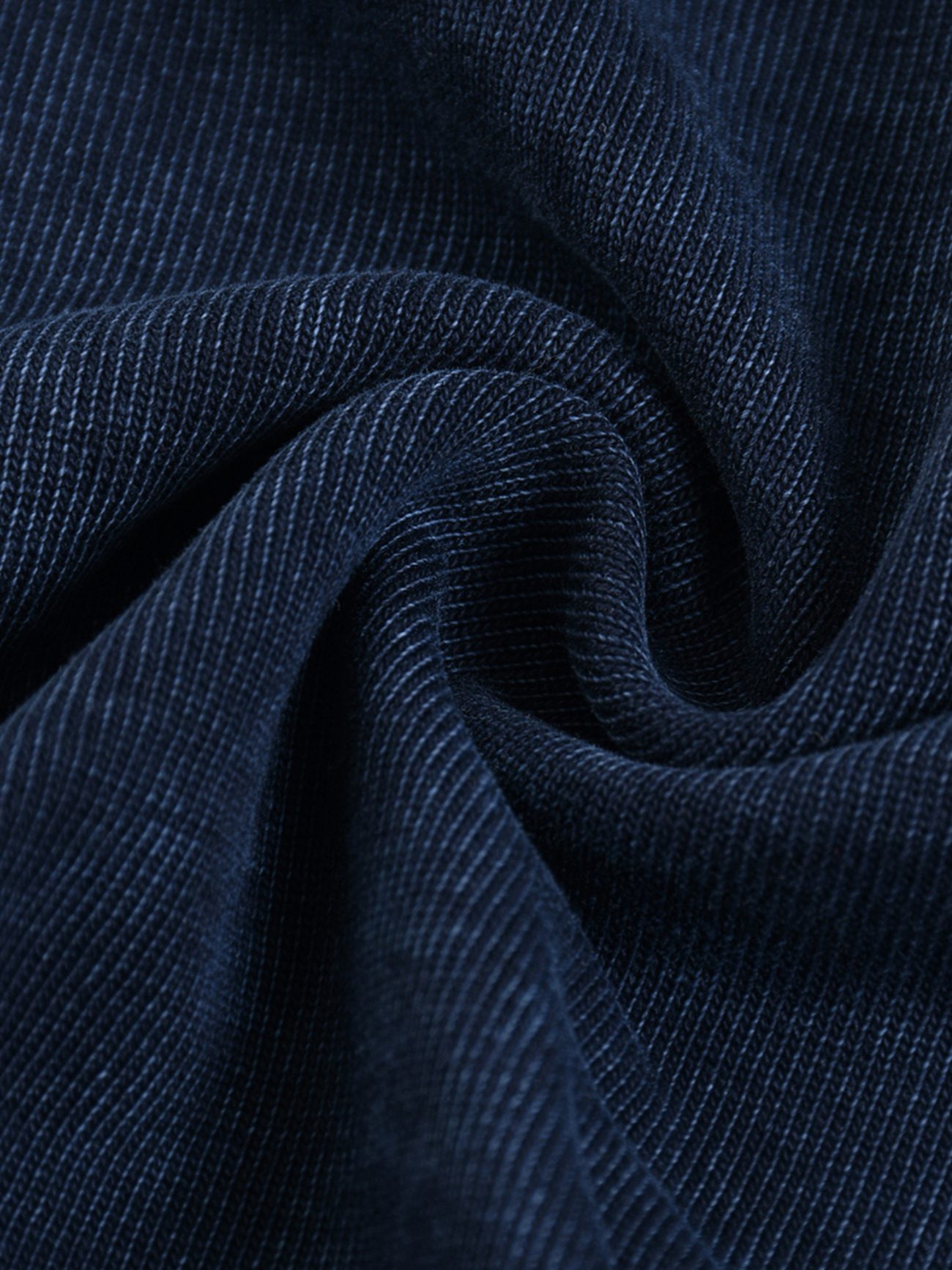Close-up of dark blue corduroy fabric with a visible ribbed texture, arranged in soft folds—an inviting detail from our affordable luxury Fusion Heavyweight Snow-Washed Polo T-Shirt collection.