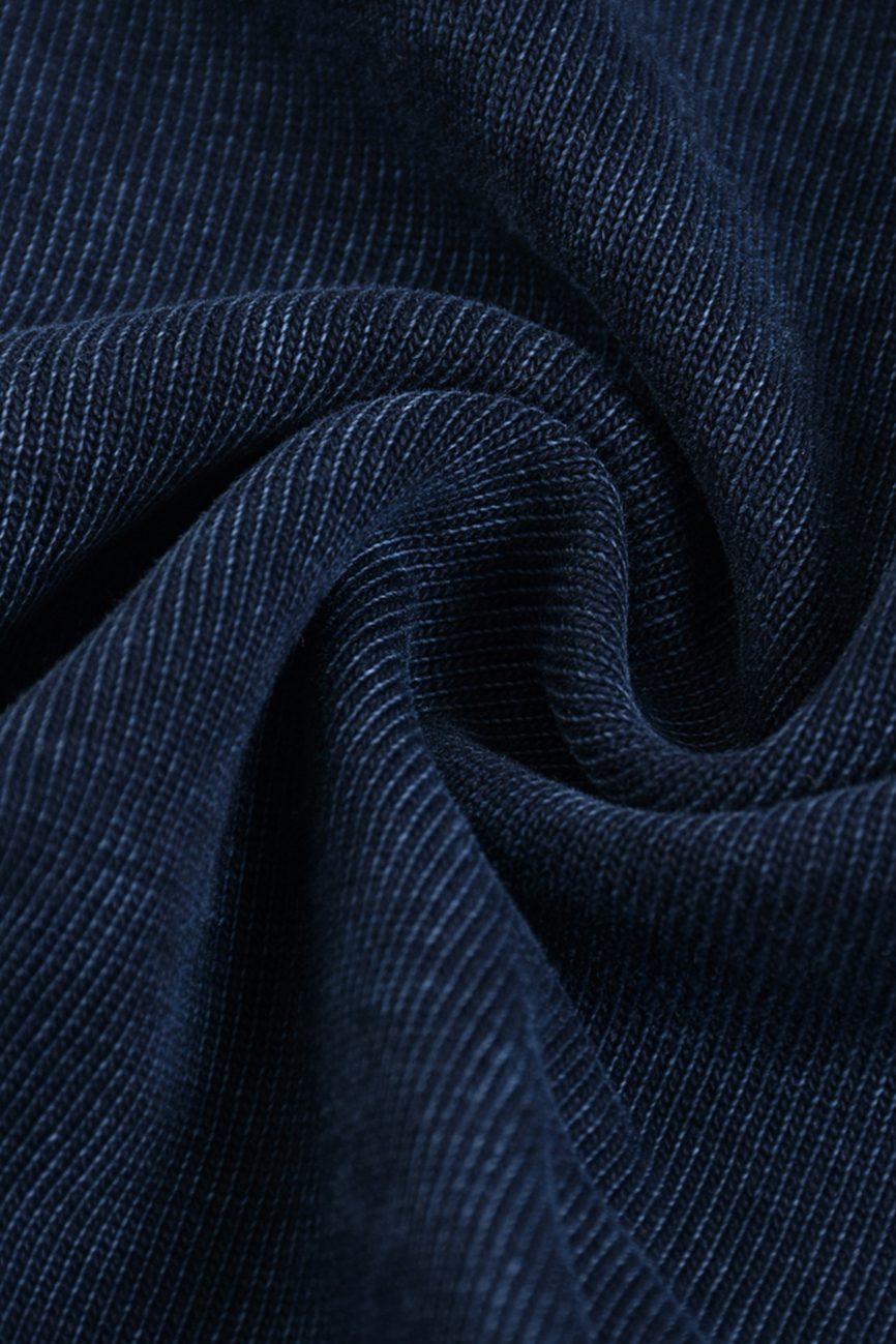 Close-up of dark blue corduroy fabric with a visible ribbed texture, arranged in soft folds—an inviting detail from our affordable luxury Fusion Heavyweight Snow-Washed Polo T-Shirt collection.