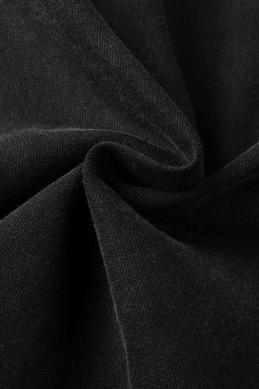 Close-up of black fabric from the Toile De Jouy - Heavyweight Vintage Washed Frayed T-Shirt, featuring soft texture with gentle folds and a central twist that forms a spiral pattern, highlighting smooth, matte elegance in affordable luxury.