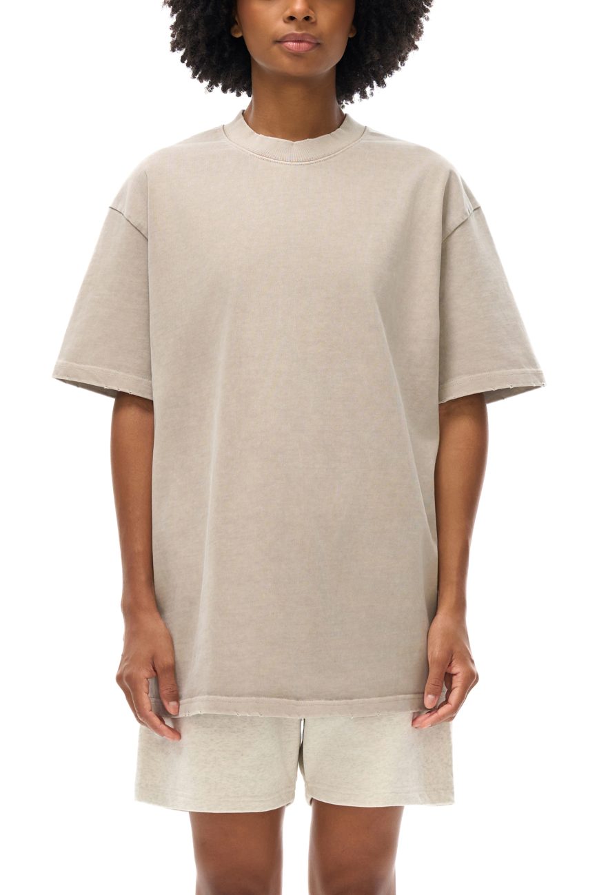 Wearing the Toile De Jouy - Heavyweight Vintage Washed Frayed T-Shirt, a person stands against a white background. Only their torso, arms, and upper legs are visible; hands rest relaxed by their sides.