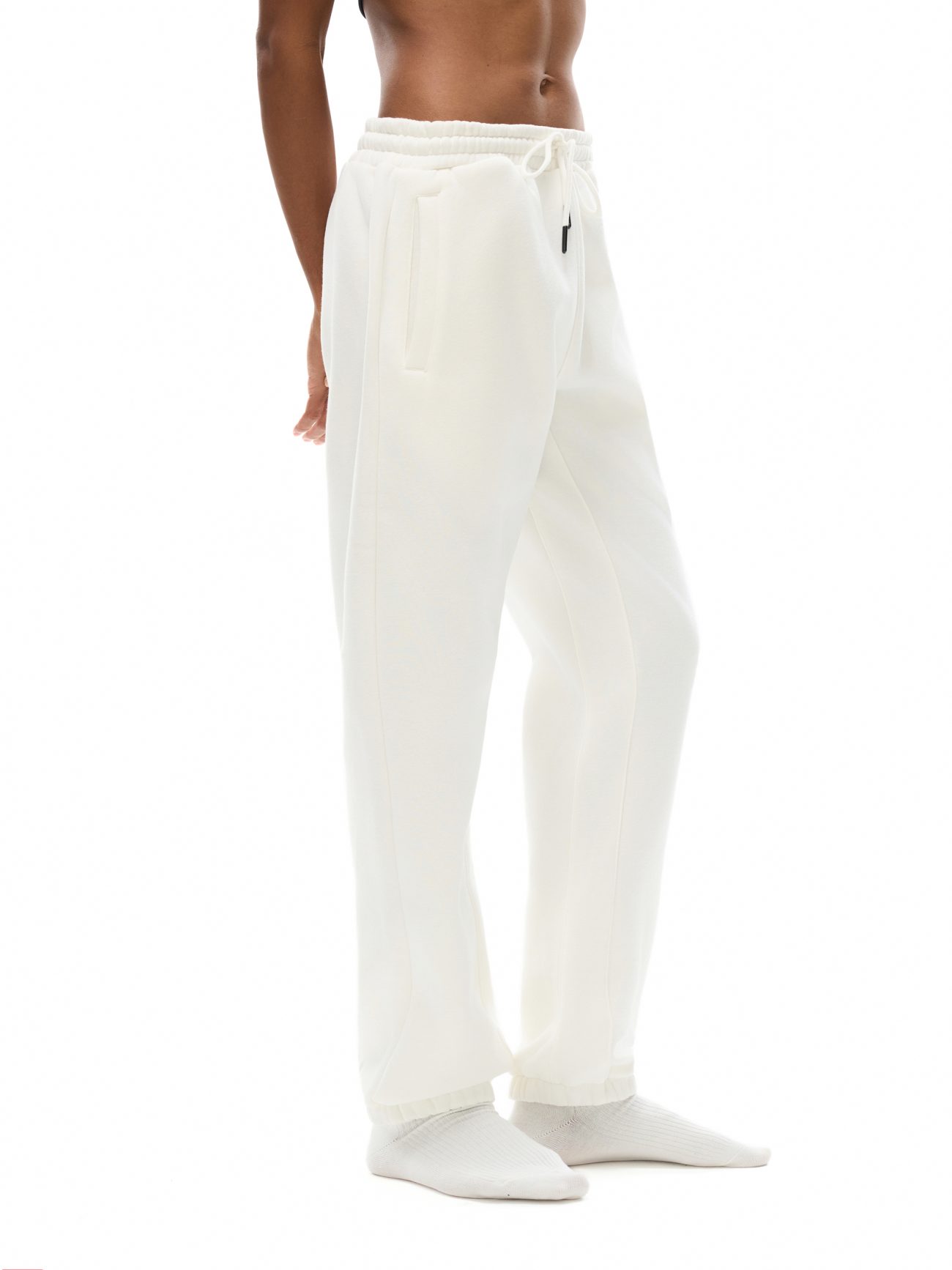 Against a plain white background, a person models Streetwear Unisex Fleece Joggers—loose-fitting with a drawstring waist—paired with white socks for an understated, affordable luxury vibe. The upper body is shirtless; the head is not shown.
