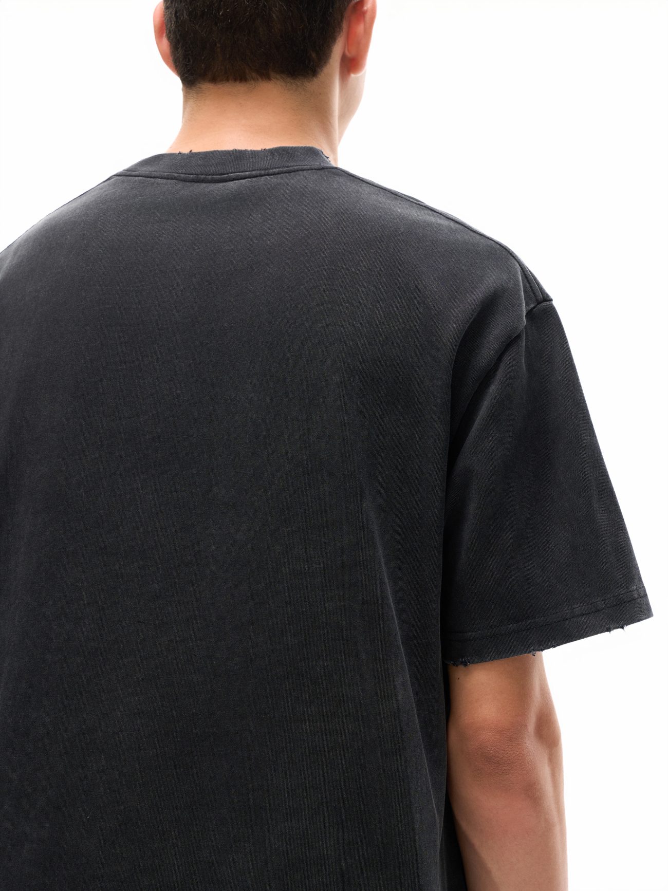 A person is shown from the back, wearing the Toile De Jouy - Heavyweight Vintage Washed Frayed T-Shirt in black, with short dark hair visible against a white background.