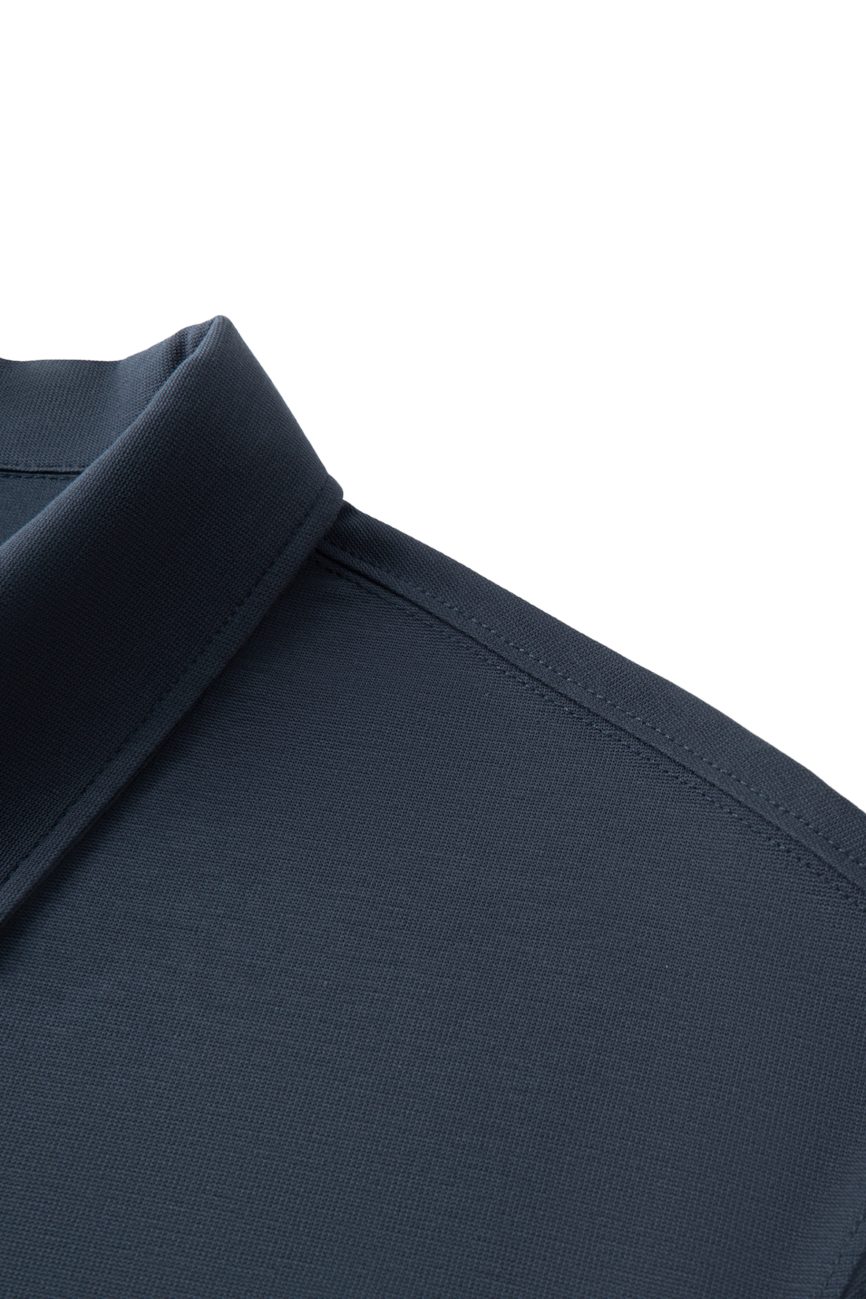 Close-up of the shoulder and collar of the FC&Co. - Drop Shoulder Short-Sleeve Polo in dark navy blue, highlighting fabric texture and stitching details. This piece embodies affordable luxury clothing against a crisp white background.