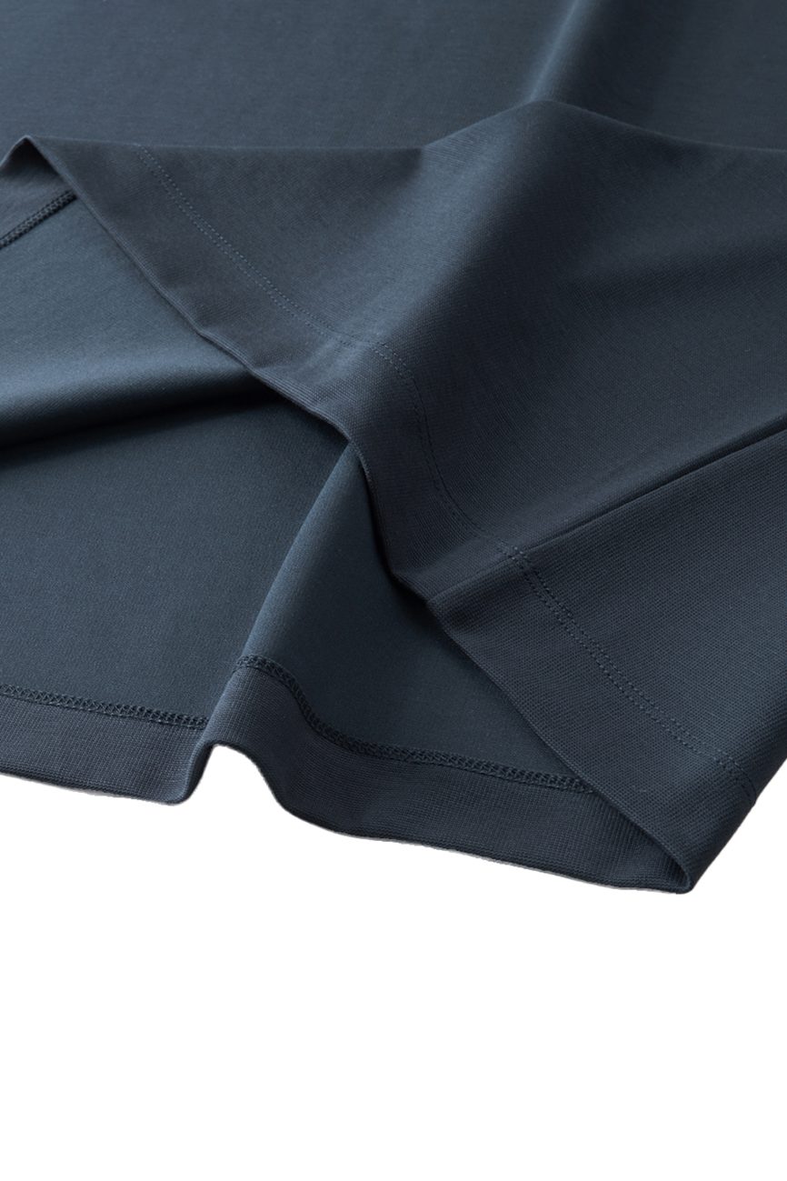 A close-up of the FC&Co. Drop Shoulder Short-Sleeve Polo, neatly folded in dark blue, highlights its smooth texture, precise hems, and visible stitching—showcasing affordable luxury and quality craftsmanship.