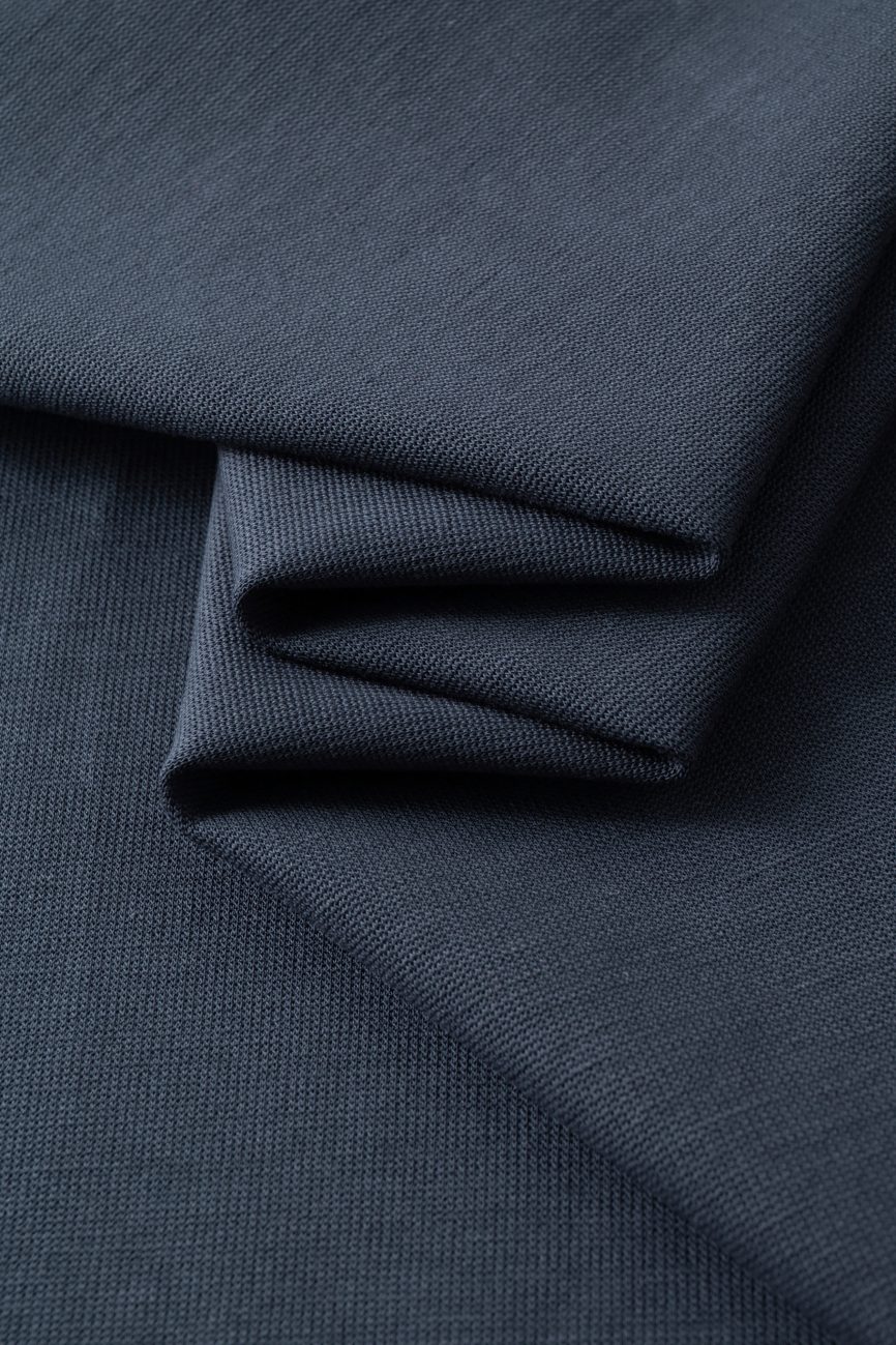 Close-up of dark blue textured fabric with neat, overlapping folds and a smooth, matte finish—ideal for the FC&Co. Drop Shoulder Short-Sleeve Polo and perfect for Affordable Luxury Clothing.