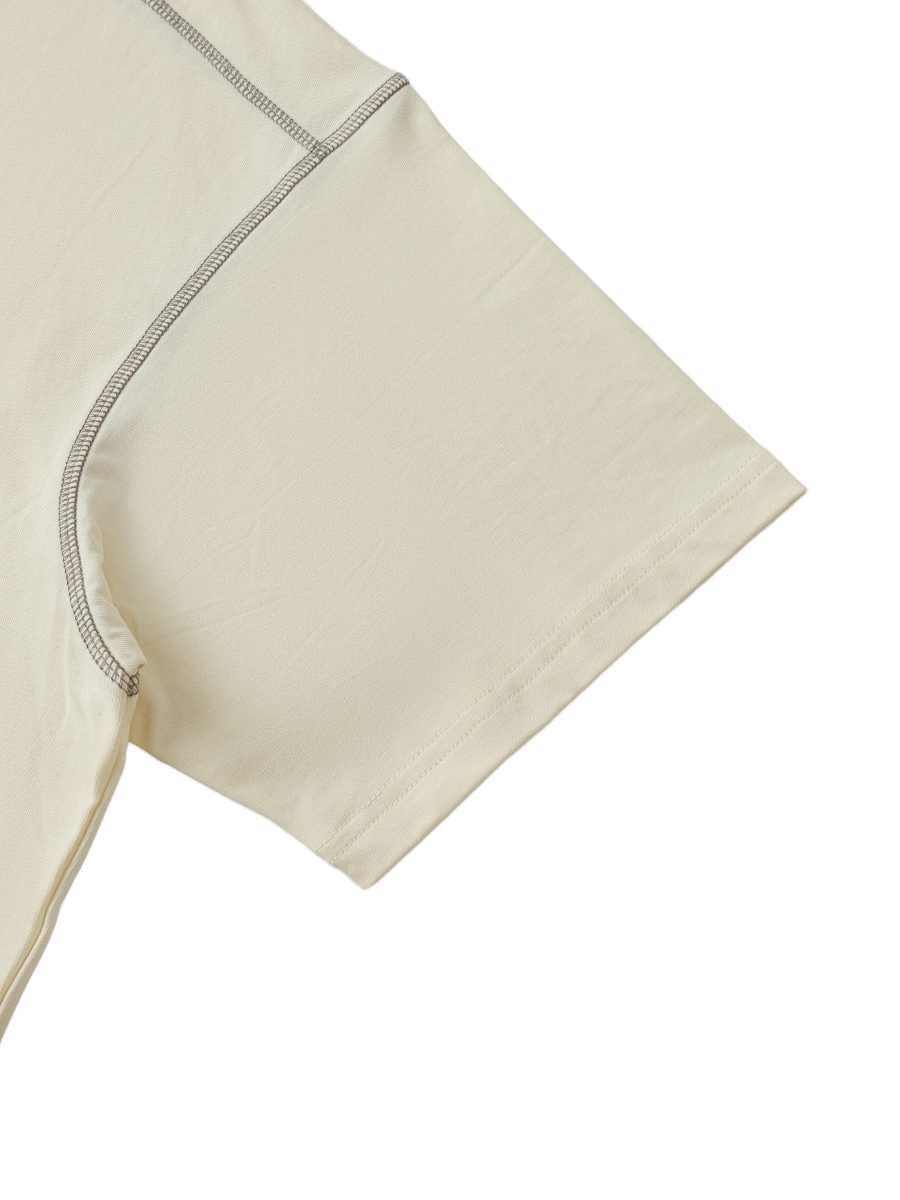 Close-up of the short sleeve and shoulder seam on the Crane - Oversized Contrast-Stitched Cotton Tee, showcasing visible stitching and smooth light beige cotton fabric.